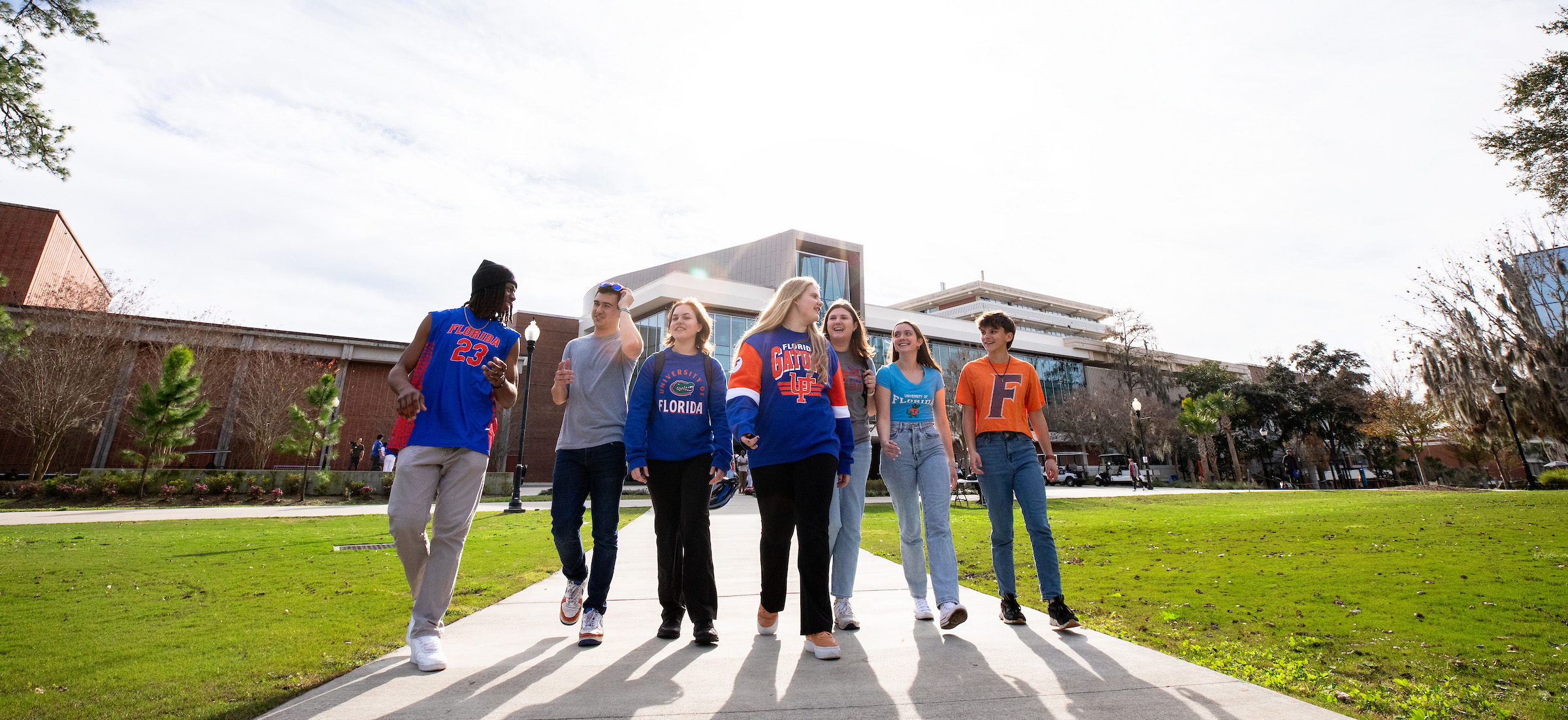 a group of students walks away from the reitz union on a sunny day smiling.