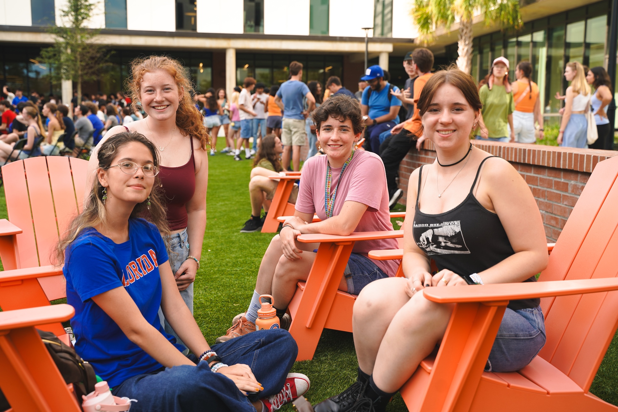 Four students sitting outside and smiling at the camera