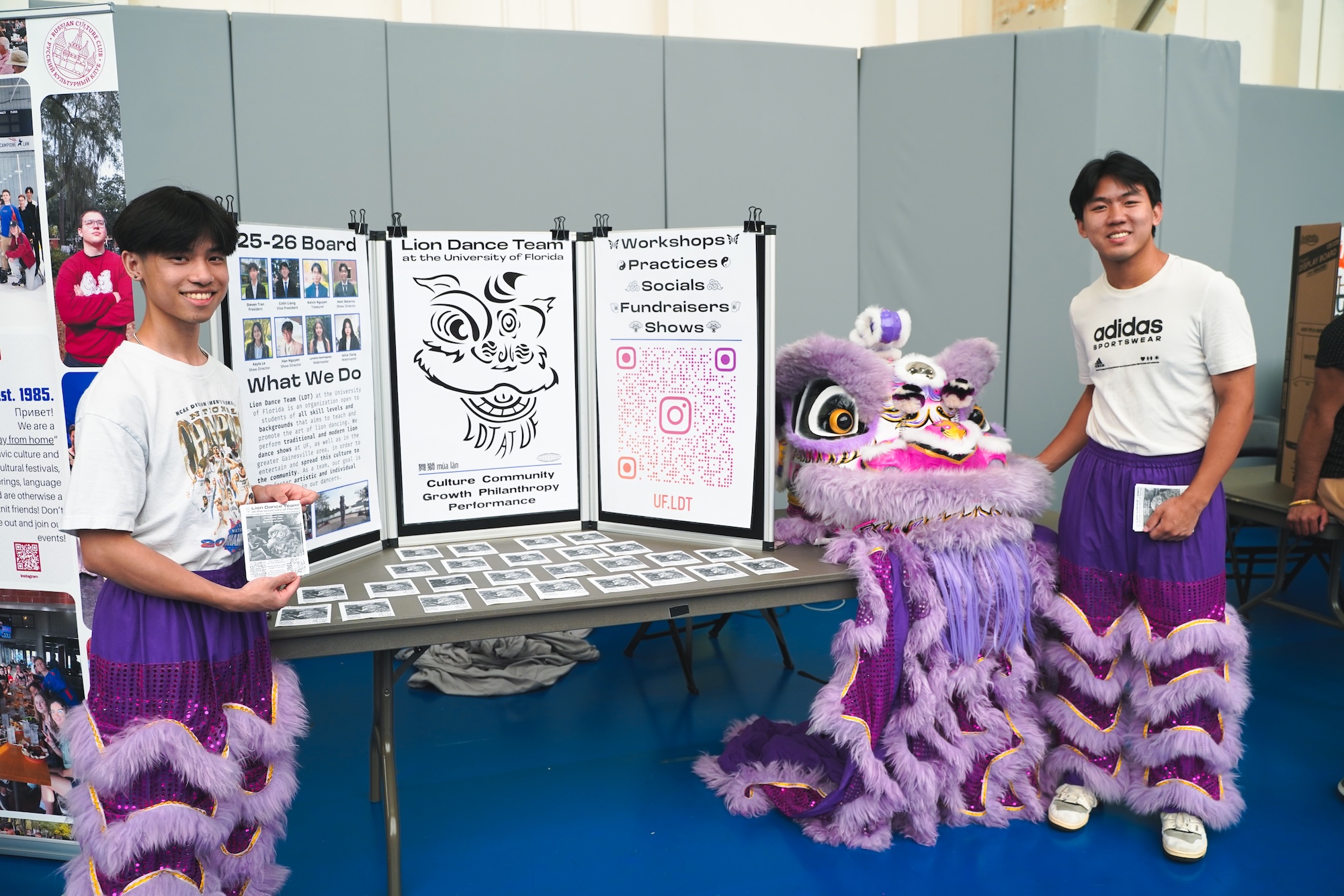 Two students smiling at the camera and standing next to their table set up at the Student Org Fair