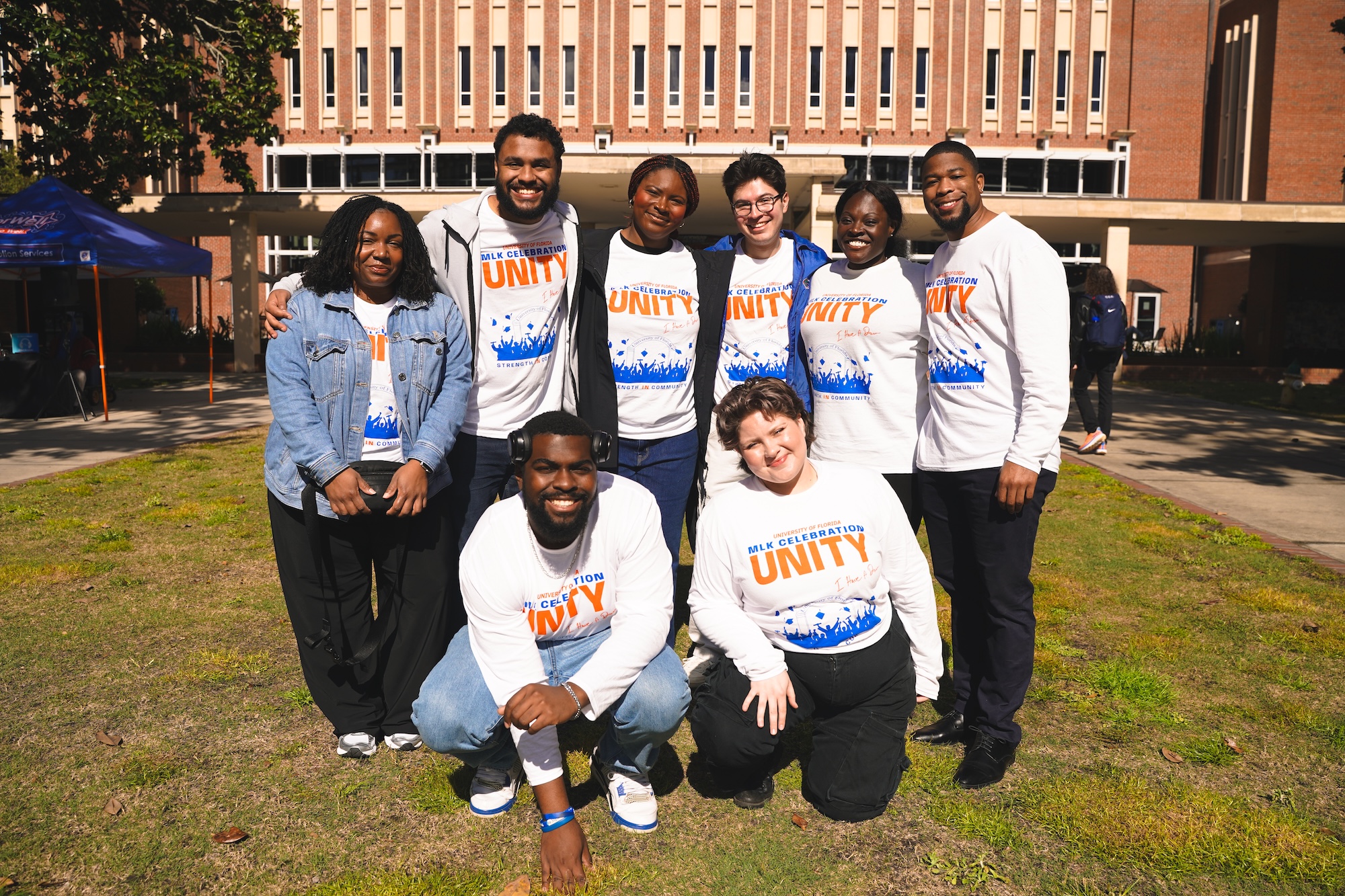 Staff wearing their UNITY Fest shirts and smiling at the camera on a bright sunny day during the UNITY Fest.